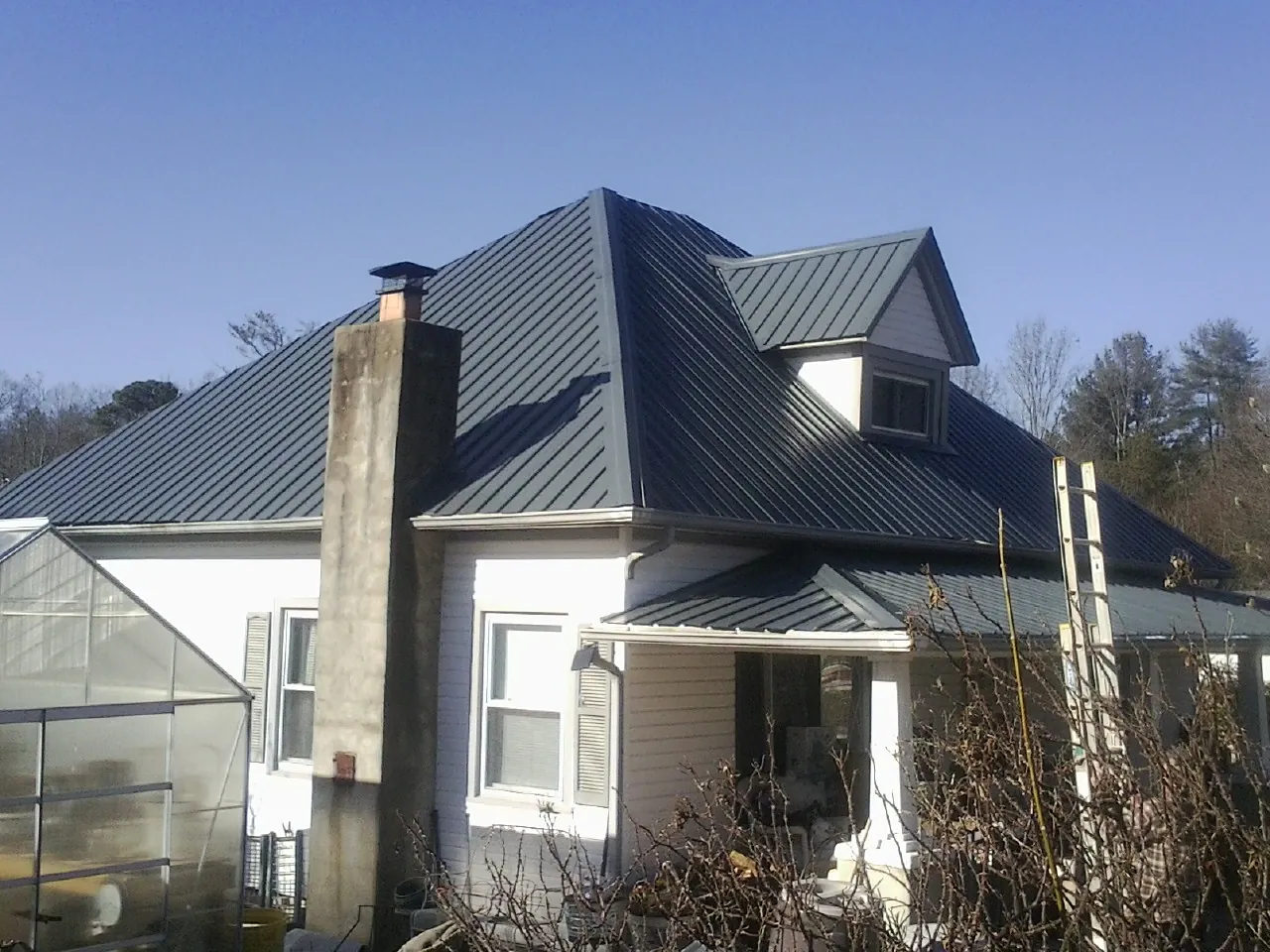 Dark blue standing seam metal roof on a white farmhouse with dormer — Slate & Tile Roof Repair by Roofing Brothers in Hubertus