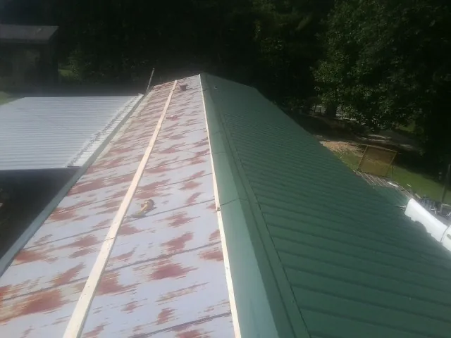 Old rusted panels beside newly installed green metal roofing — Wind Damage Roof Repair by Roofing Brothers in Hubertus
