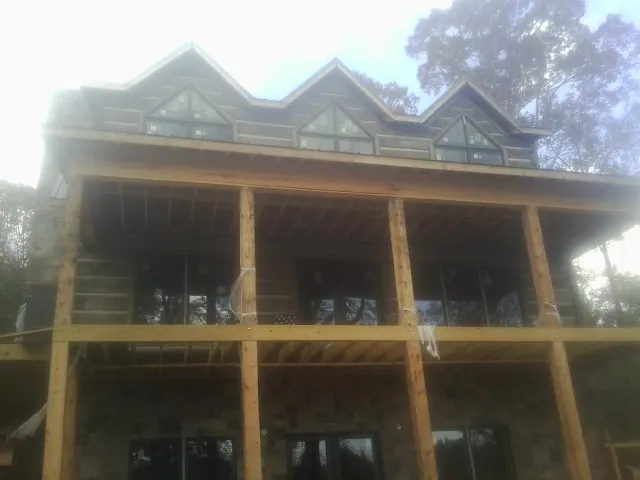 Dormers and porch framing on a large log home under construction — Roof Coating work by our crew in Hubertus