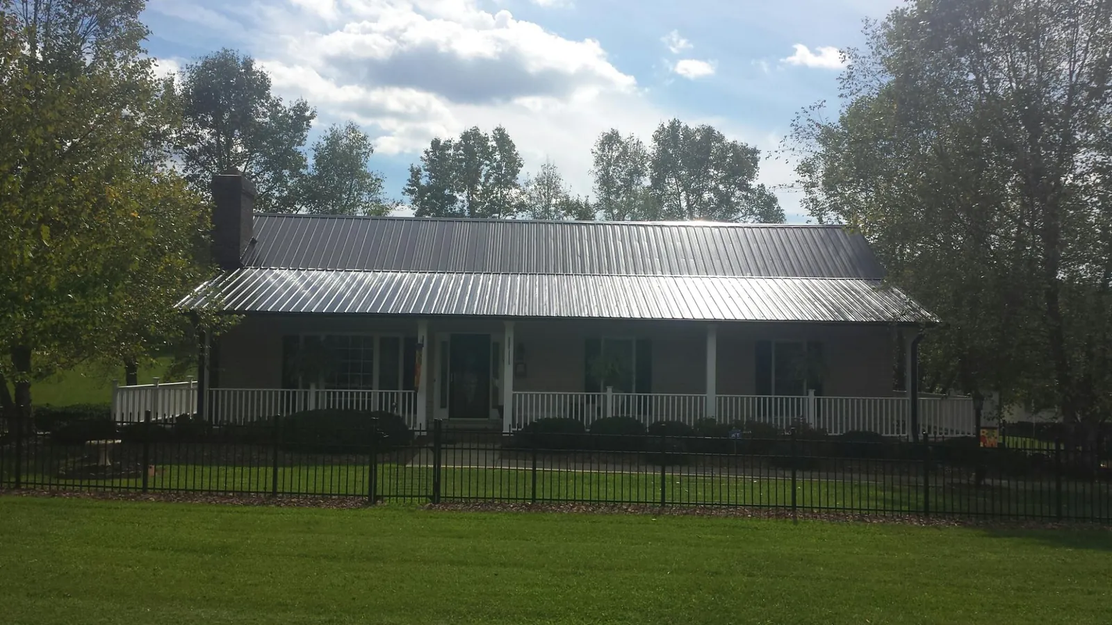 Gray metal roof on a brick ranch with a full width front porch — Gutter Guard Installation work by our crew in Hubertus