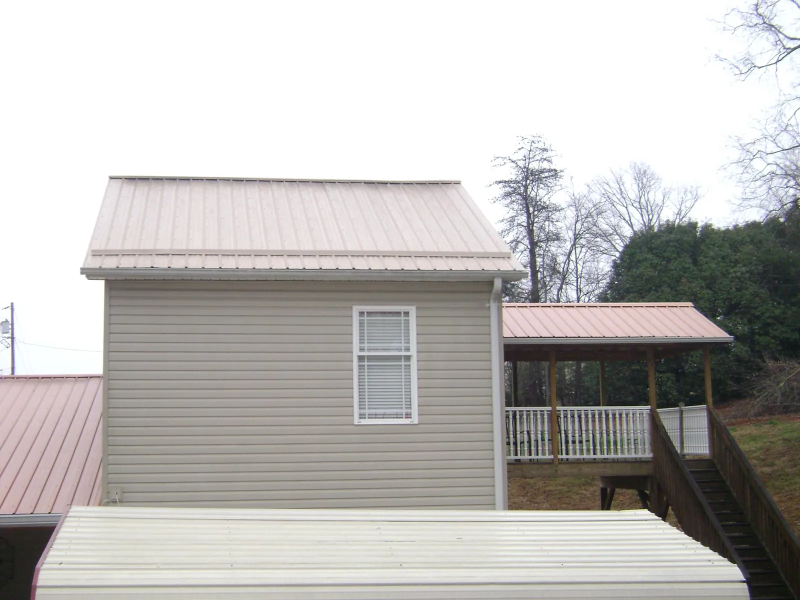 Tan metal roofs on a two story addition and attached porch, from a Roof Replacement job in Hubertus
